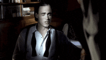 a man wearing a bow tie and suspenders looks at another man