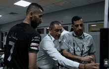 a man wearing a shirt that says emaar is talking to another man