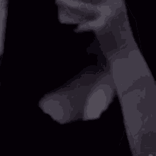 a man in a suit and tie is standing in a dark room holding a glass of wine .