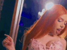 a woman with long red hair is sticking her tongue out while standing next to a window .