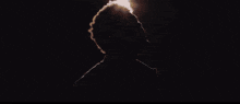 a silhouette of a man in a dark room with a light shining on his face