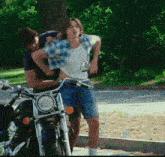 a man is holding another man 's waist while riding a motorcycle