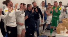 a group of soccer players standing in a locker room with one wearing a green and yellow jersey with the number 1 on it