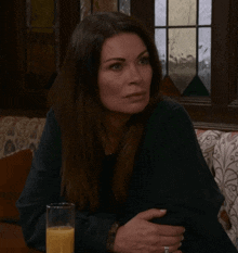 a woman is sitting at a table with a glass of orange juice