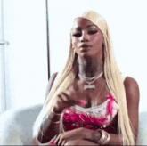 a woman with long blonde hair is sitting on a couch and making a funny face .