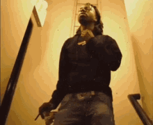 a man is smoking a cigarette while standing on a set of stairs .