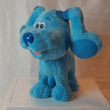 a blue stuffed animal is sitting on a white shelf