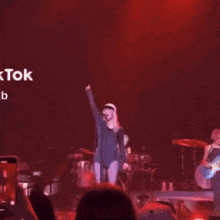 a woman singing in front of a crowd with a sign that says tok