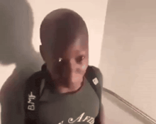 a young boy wearing a backpack is standing in a hallway .