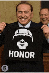 a man in a suit is holding a black shirt that says honor on it