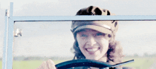 a woman wearing a hat is smiling in a car window