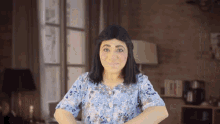 a woman wearing a wig and a blue shirt is standing in a living room