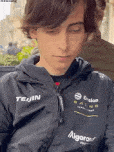 a young boy wearing a teijin racing jacket is looking down