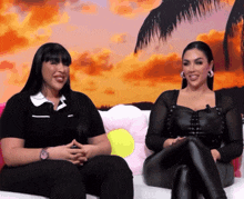 two women are sitting next to each other on a couch and smiling