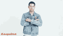 a man in a blue denim jacket is standing with his arms crossed in front of an esquire ad