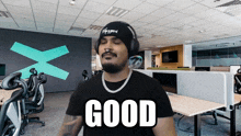a man wearing headphones and a black shirt with the word good on it
