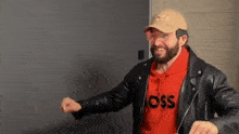 a man with a beard wearing a hat and a leather jacket .