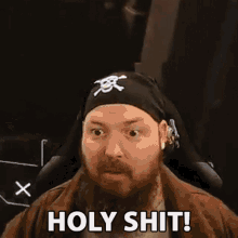 a man with a beard and a bandana on his head is sitting in a chair .
