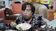a man is eating a bowl of food with a green spoon in front of a yellow stuffed animal that says minion