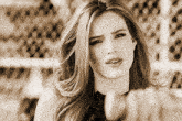 a woman 's face is shown in a black and white photo with a fence in the background