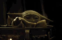 a close up of a baby yoda from star wars sitting in a crib .