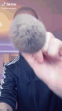 a person is holding a brush in front of their face and a tiktok video is being displayed