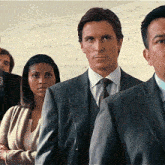 a man in a suit and tie is standing in a line with other people