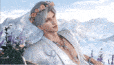 a man wearing a flower crown is sitting in front of mountains