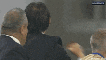 a man in a suit is being escorted by a man in a white shirt and a cbs sports logo is visible
