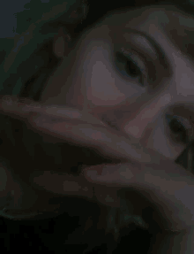 a close up of a woman covering her face with her hand