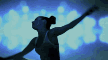 a woman is dancing in front of a blue light