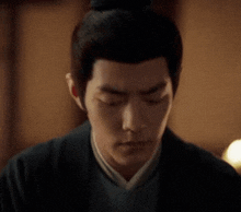 a man with a bun on his head is looking down .