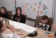 a group of children are sitting around a table with a poster that says " build a tree with wings " on it