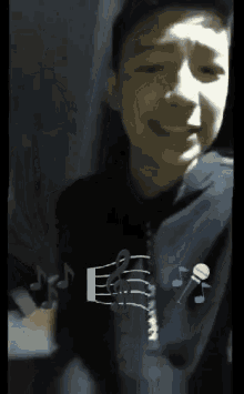 a young boy wearing a black shirt with music notes and a microphone on it .