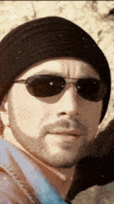 a man with a beard wearing a black hat and sunglasses