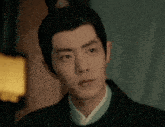 a man with a crown on his head is wearing a black jacket and a white shirt .