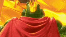 a green statue with a red cape and a crown on top