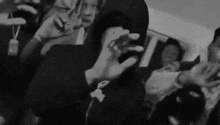 a group of people are standing around a man in a hooded jacket .