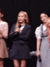 a woman in a suit is holding a microphone in front of a group of women
