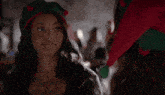 a woman wearing a christmas hat is standing next to another woman wearing a santa hat .