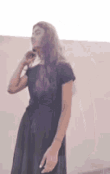 the woman is wearing a black dress and talking on a cell phone .