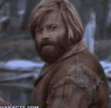 a man with a beard and long blonde hair is looking at the camera .