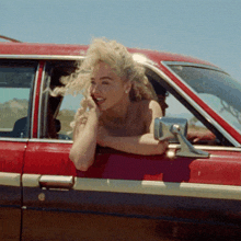 a woman leans out of the window of a car