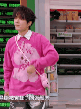 a man wearing a pink sweater with a bear on it
