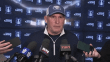 a man speaking into a tsn microphone in front of a stanley cup playoffs backdrop