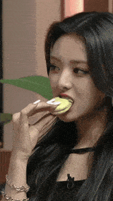 a woman with long black hair is eating a cookie