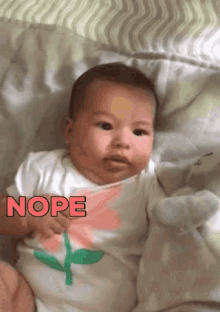 a baby is laying on a bed with the word nope written on his shirt