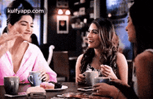 a group of women are sitting at a table drinking coffee and eating desserts .