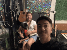 a man and a woman are posing for a picture in front of a guitar that has the letter a on it
