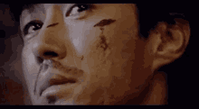 a close up of a man 's face with blood running down it .